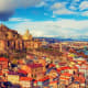 Tbilisi skyline with historic Narikala Fortress on hilltop overlooking colorful old town buildings and distant mountains unde